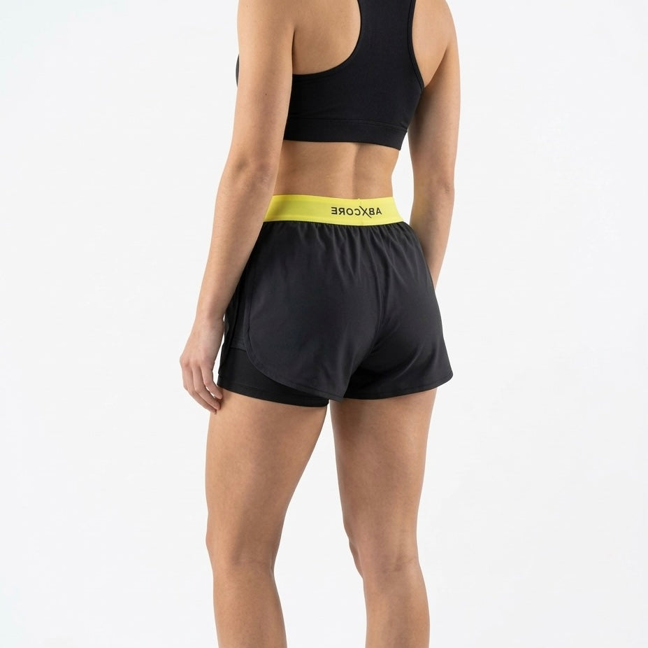 woman wearing black ABXCORE women’s training short with yellow waistband back view